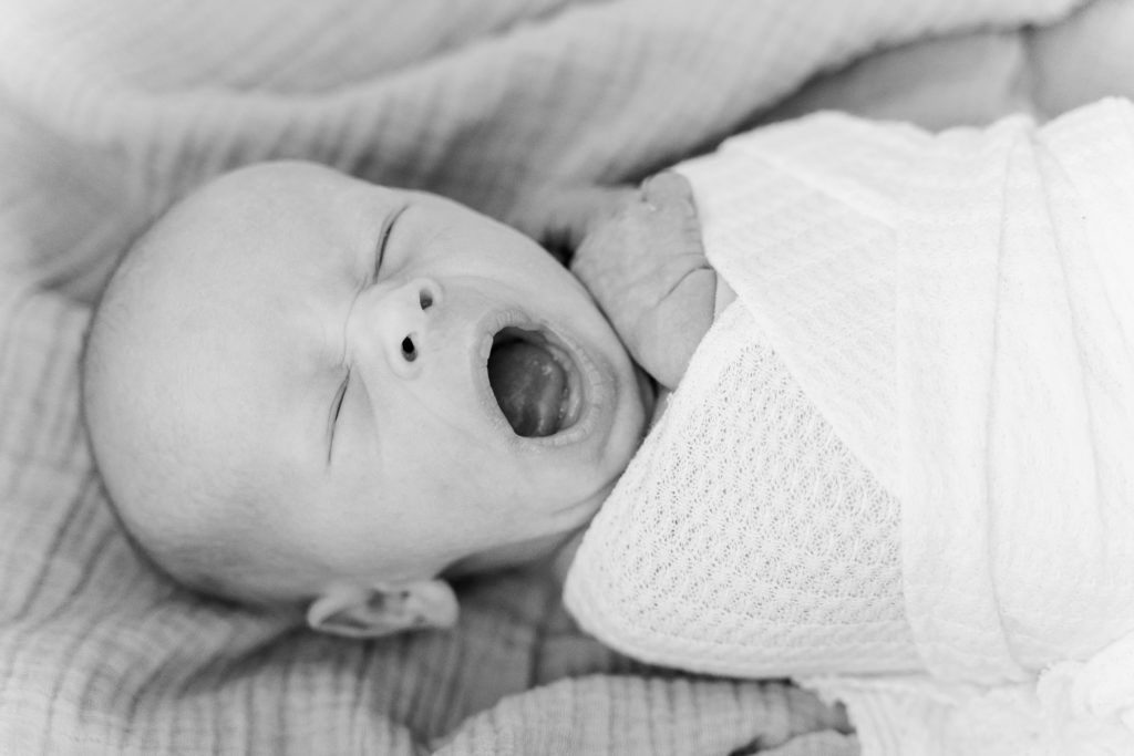 Light and airy newborn boy portrait yawning