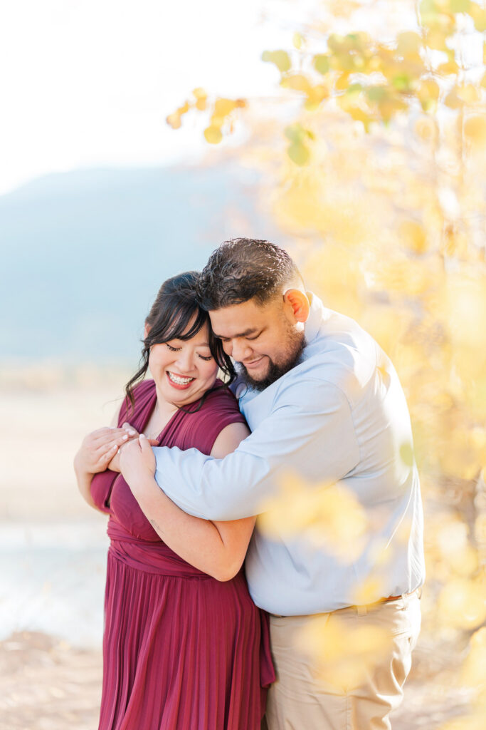 Cathie and Jesse share a joyful embrace surrounded by golden fall aspen leaves.