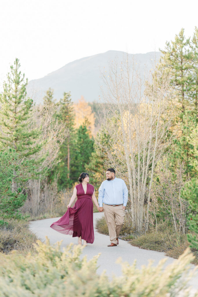 Cathie and Jesse walk hand in hand along a peaceful mountain trail during their Colorado fall engagement session.