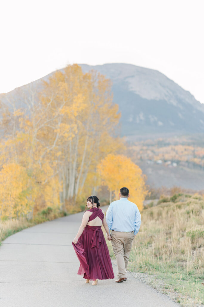 Cathie and Jesse walk together along a winding path lined with brilliant yellow aspen trees.