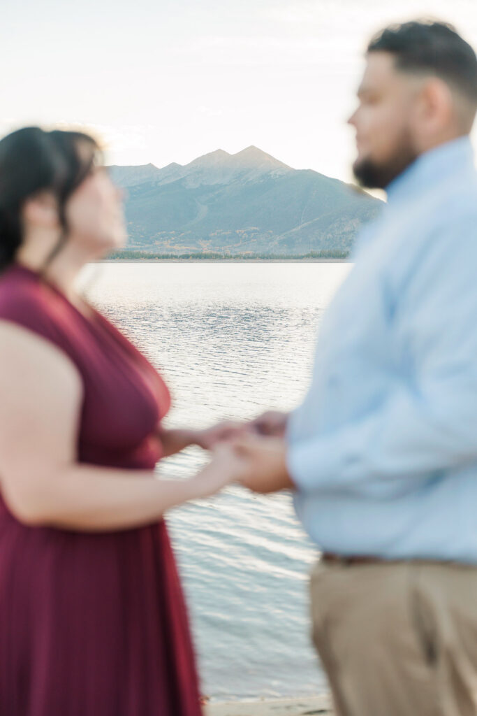 Colorado mountain peaks across Lake Dillon framed by a softly blurred Cathie and Jesse holding hands.